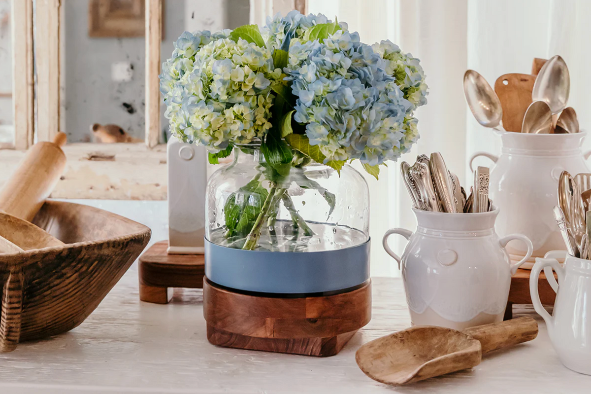 Decorative items including a vase with flowers, wooden bowls, and kitchen utensils on a table.