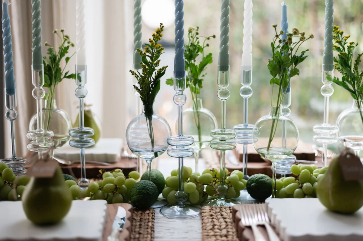 Decorative table setting with green apples, candles, and plants.